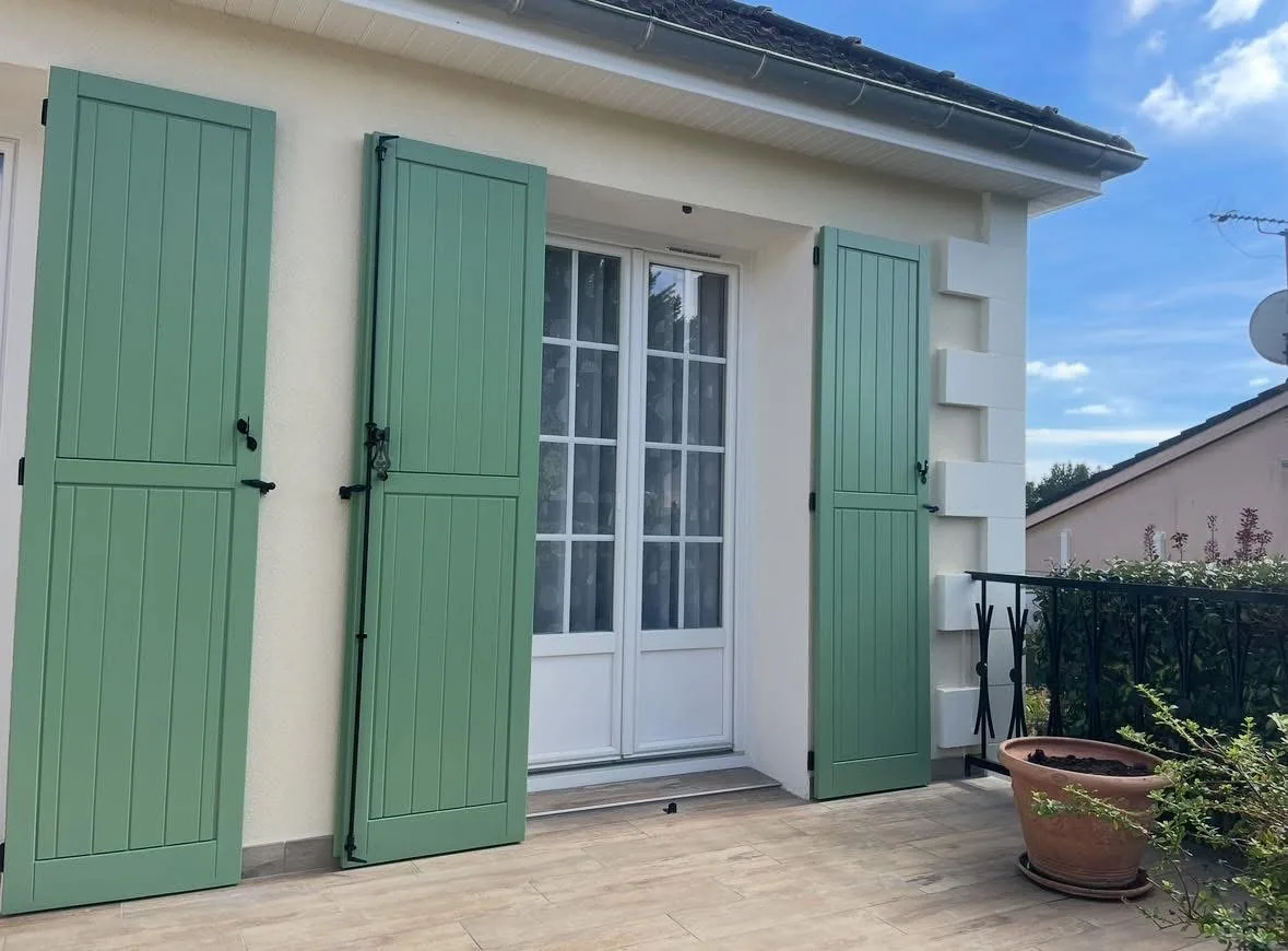 Volets battants verts reposés sur une façade isolée par l'extérieur, encadrements finis