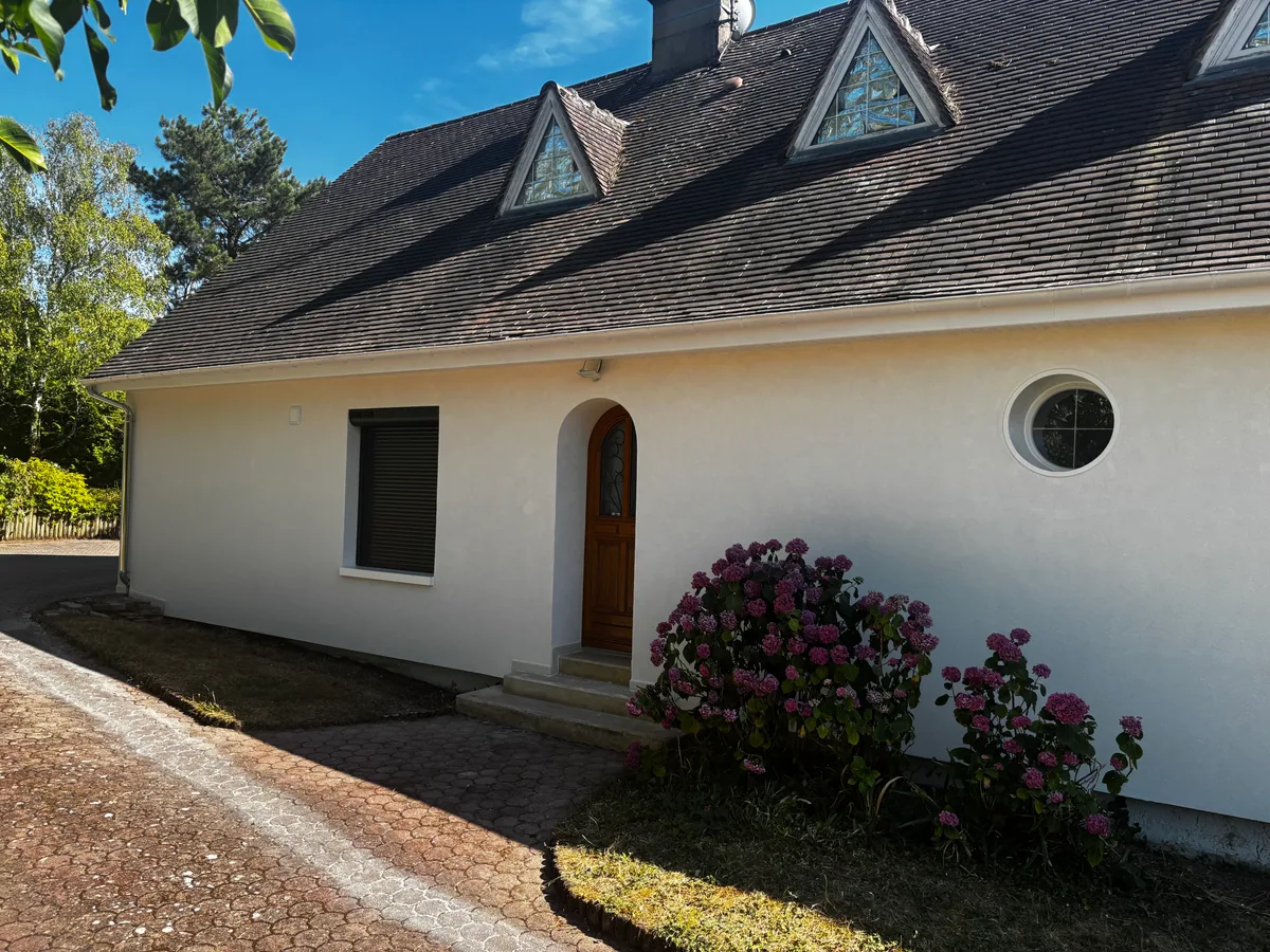 Façade blanche isolée par l'extérieur en plein soleil, porte cintrée et œil-de-bœuf