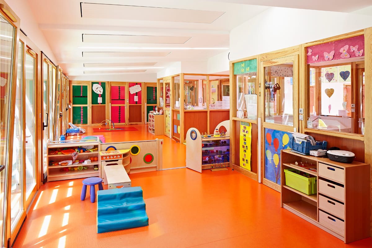Salle d’activités aux murs orange vif et cadres de portes en bois clair