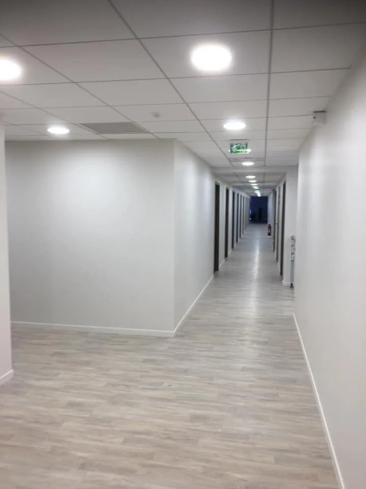Couloir de bureaux terminé, murs peints en blanc et sol souple clair