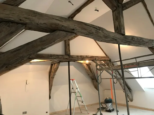 Combles aménagés sous charpente ancienne, plaques de plâtre posées entre les poutres