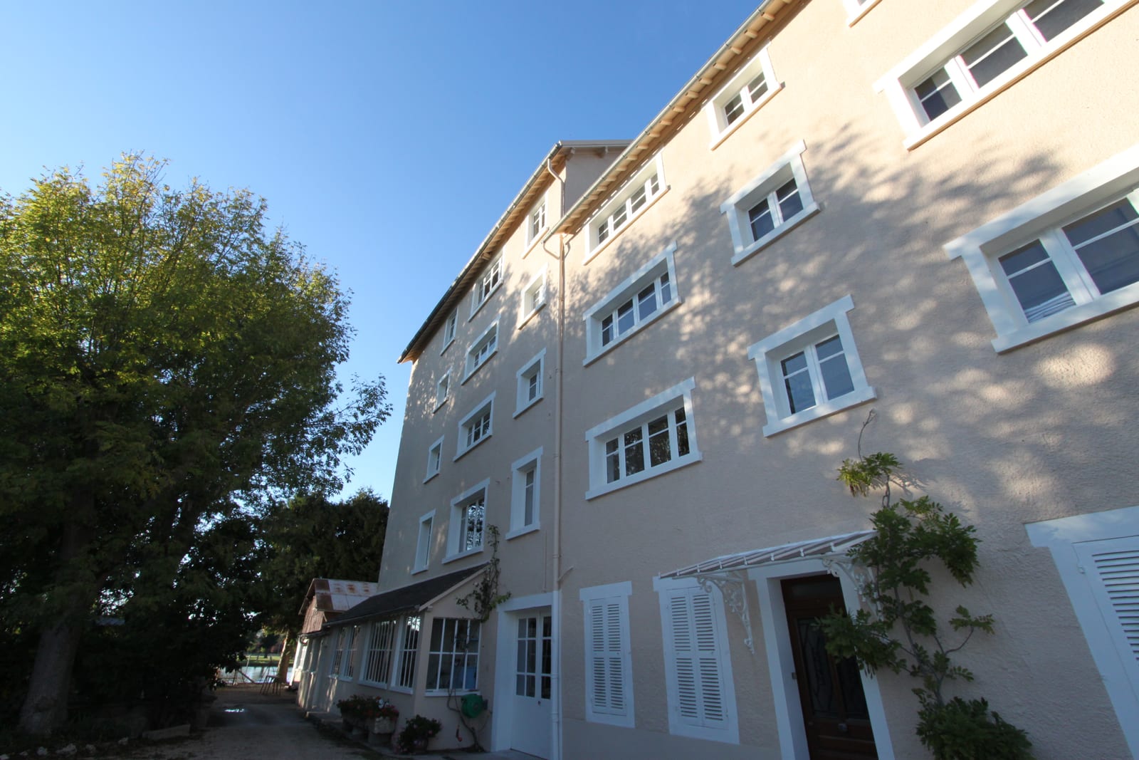 Façade du Moulin de Vincelottes ravalée, peinture rose pâle et encadrements blancs